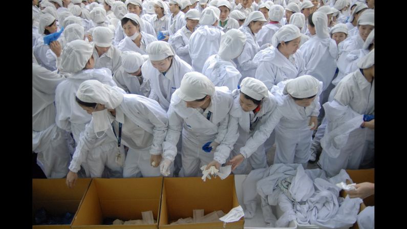 Migrant workers at an electronics factory take off protective clothing following a fire evacuation drill. 