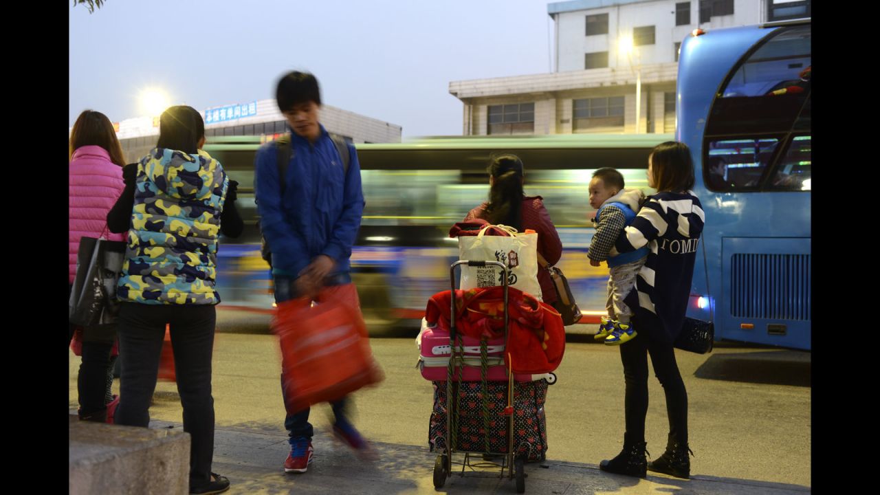 Migrant workers wait along the side of a road in Dongguan, southern China, for a coach to take them back to their hometowns.