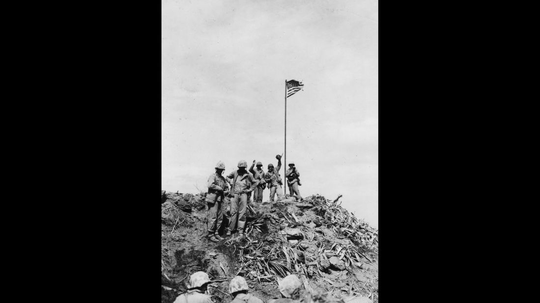 Marine Pfc. Bob Campbell shot this photo of Rosenthal standing with Marines near the first flag. Rosenthal can be seen waving his camera in the air. 