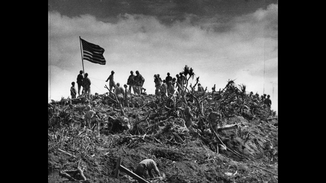 Marines gather on the summit after replacing the smaller American flag with a larger one. The photographer of this image is uncredited. 