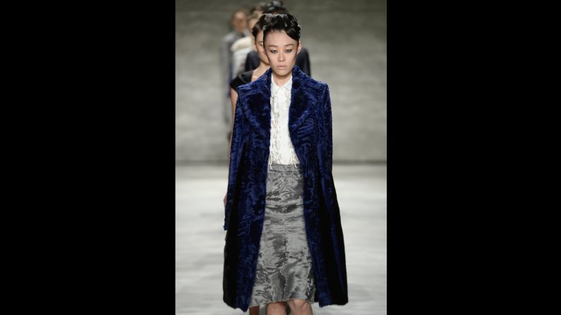A model presents an indigo fur coat, tuxedo blouse and gray fur skirt for Bibhu Mohapatra.