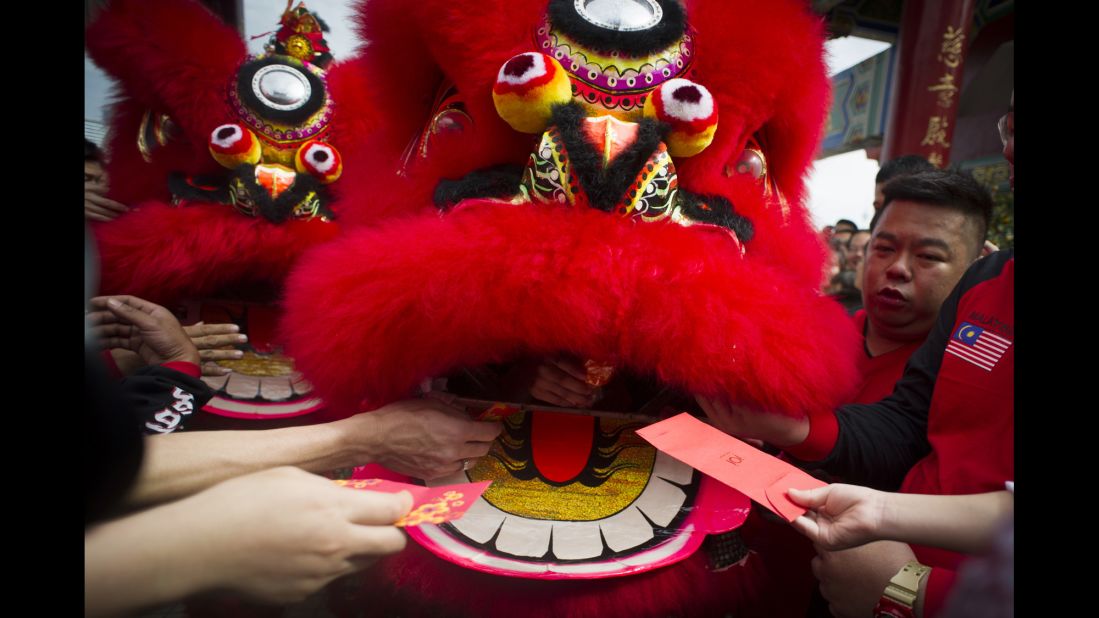 Temple visitors give red envelopes with money to a lion dance troupe during a performance in Kuala Lumpur, Malaysia, on February 19.
