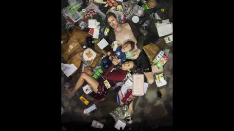Photographer Gregg Segal gives himself a reality check by posing with one week of his family's trash.