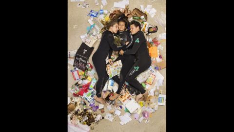 Susan, Curtis and Brittany cuddled up on the beach in wetsuits in their "7 Days of Garbage" shoot.