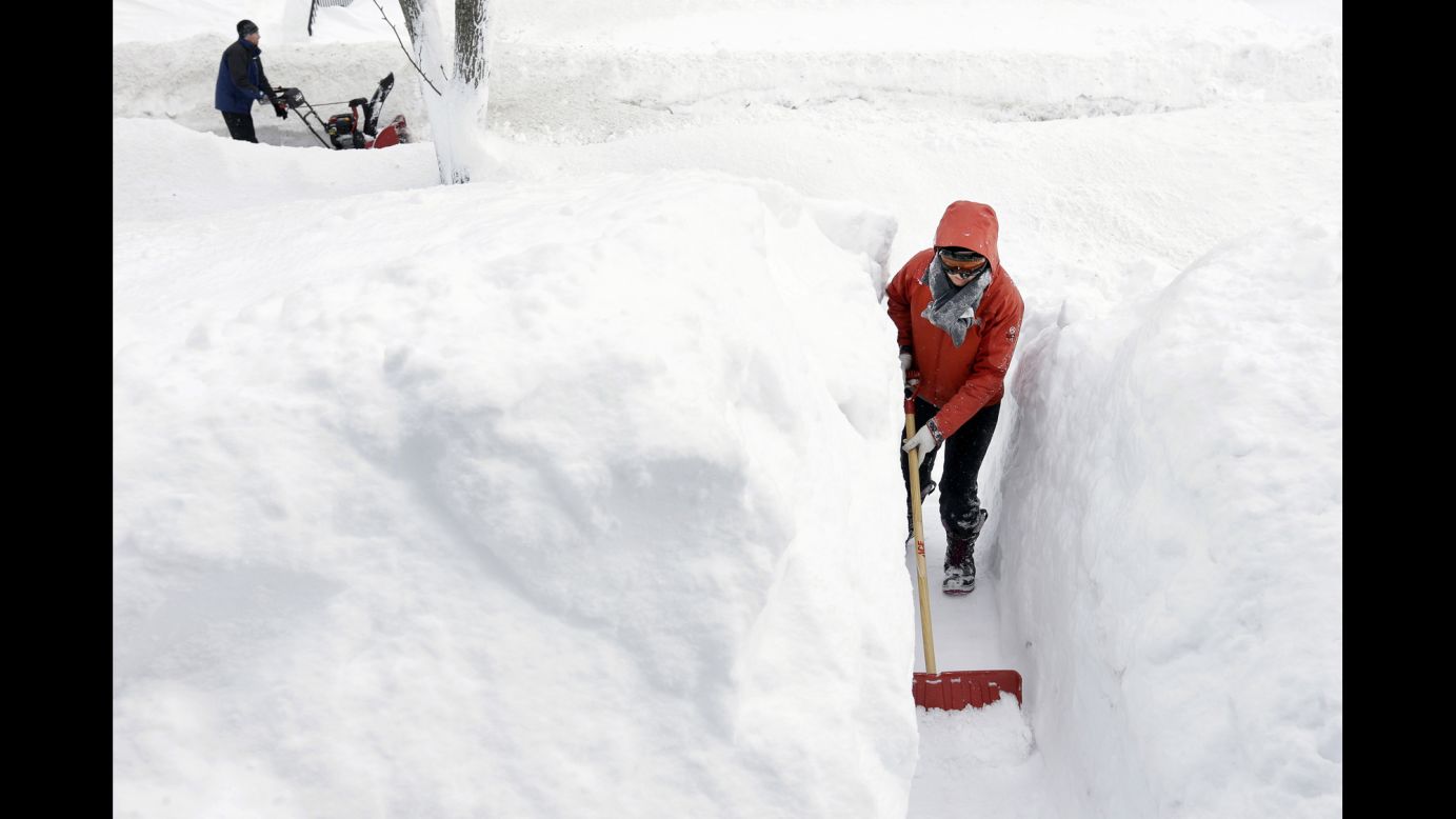 A woman shovels snow in front of her home in Norwood, Massachusetts, on Sunday, February 15.