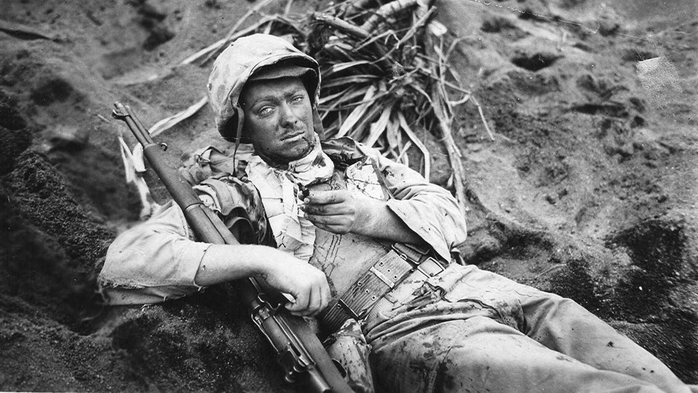 Cpl. Rudolph E. Engstrom rests in a shell hole on Iwo Jima, holding a piece of shrapnel that wounded him.