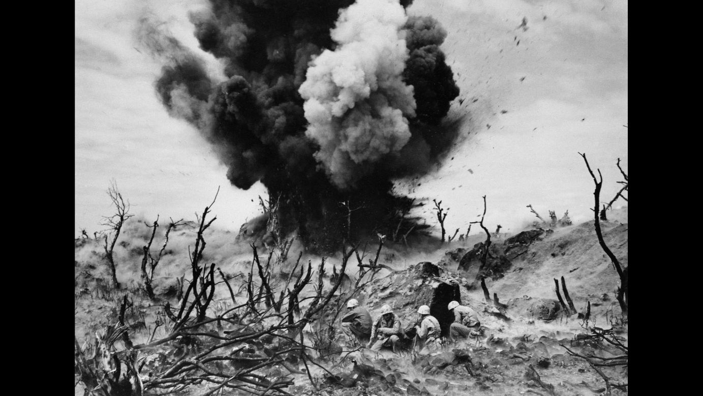 US Marines take cover as a cave is blown up on Iwo Jima.