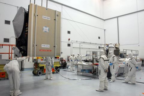 Workers check on the spacecraft, at left, as they prepare to mate it with the upper stage booster rocket on the right.