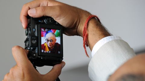 A man takes a picture of the Dalai Lama upon his arrival at the airport in Blagnac, France, on August 12, 2011. That same year, the leader approves amendments to the exiled constitution, formally removing his political and administrative responsibilities.