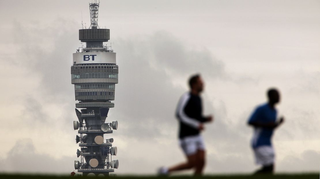 BT (British Telecom) Tower looms over two runners in Primrose Hill in London. 