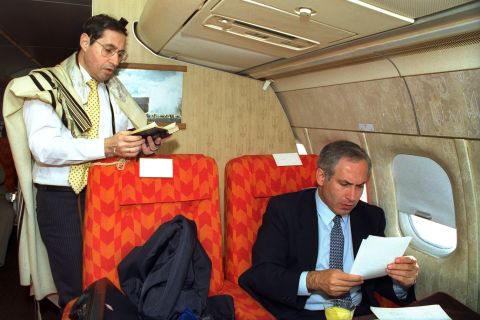 Netanyahu, as Israel's deputy foreign minister, goes through some papers as Government Secretary Elyakim Rubinstein recites morning prayers during a flight to Washington, DC, in 1989.