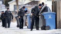 Minneapolis police officers search garbage and recycling bins in an alley after a Minneapolis police officer was shot on Saturday, February 21 in Minneapolis.