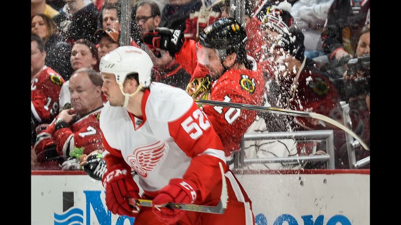 Ice goes flying after Detroit's Jonathan Ericsson, left, checked Chicago's Patrick Sharp during an NHL game in Chicago on Wednesday, February 18.