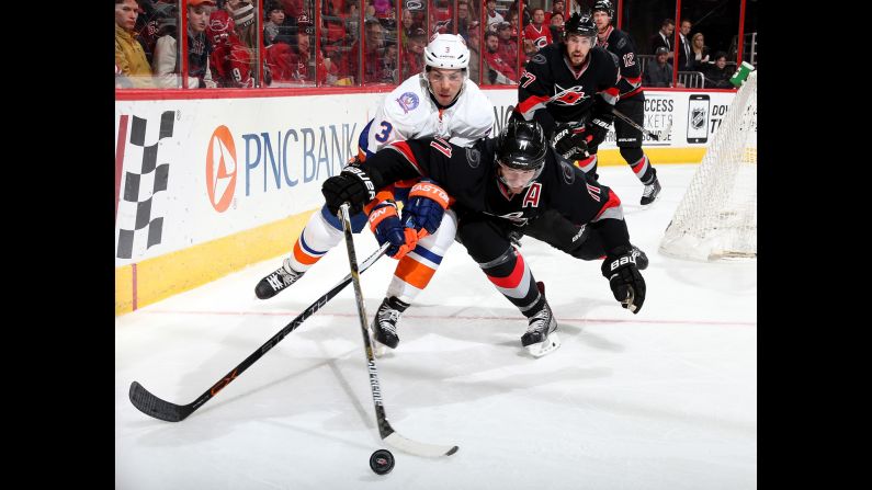Travis Hamonic of the New York Islanders, left, and Jordan Staal of the Carolina Hurricanes battle for a puck during an NHL game in Raleigh, North Carolina, on Tuesday, February 17.