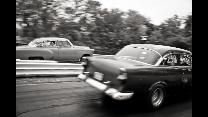 Classic cars race down a stretch of track.