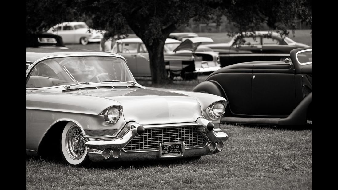 Various makes and models of classic cars are seen on the grounds of a show.