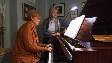 Heidi Thomas plays piano as her mother, Greta Lea Johnson, turns the pages.