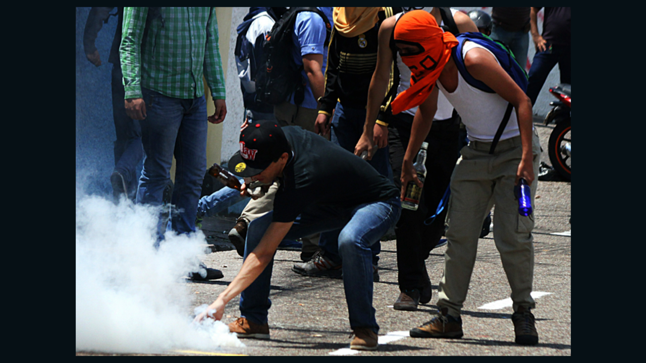 Students stand in front of a line of riot police during a protest Tuesday in San Cristobal.