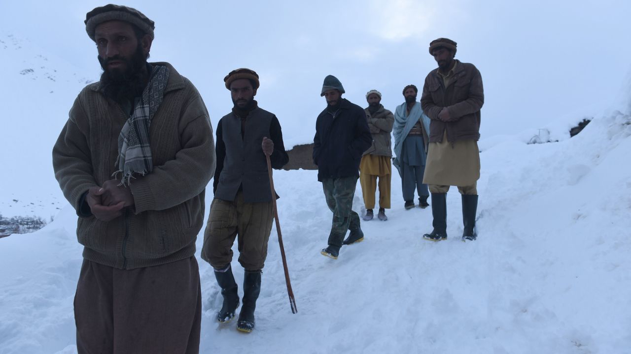 Men make their way down a slope after searching for victims in Bazarak district on Wednesday, February 25.