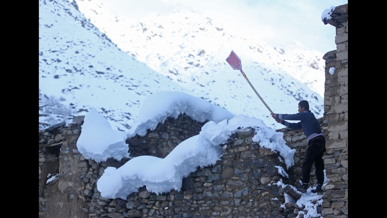A teenager cleans off snow from the roof of his house in Panjshir province February 25.