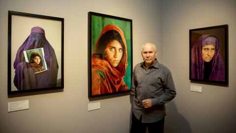 Photographer Steve McCurry poses next to his photos of the "Afghan Girl" named Sharbat Gula at the opening of the "Overwhelmed by Life" exhibition at the Museum for Art and Trade in Hamburg, Germany in 2013.