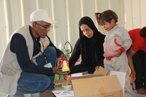 A CARE aid worker distributes food to a Syrian refugee family.  CARE has 230 staff in the Syrian region and has been working on the humanitarian crisis since the beginning. 