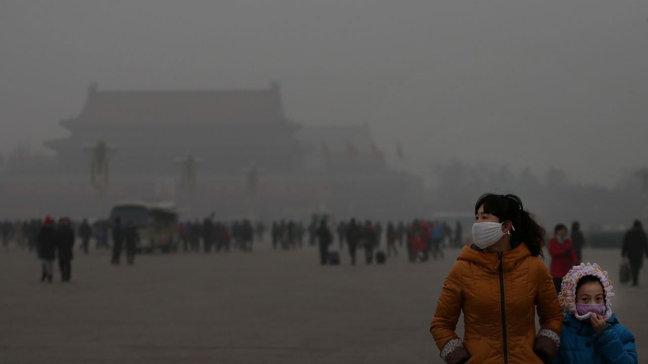 People wear masks in Tiananmen Square in 2013 as heavy smog hangs over Beijing.