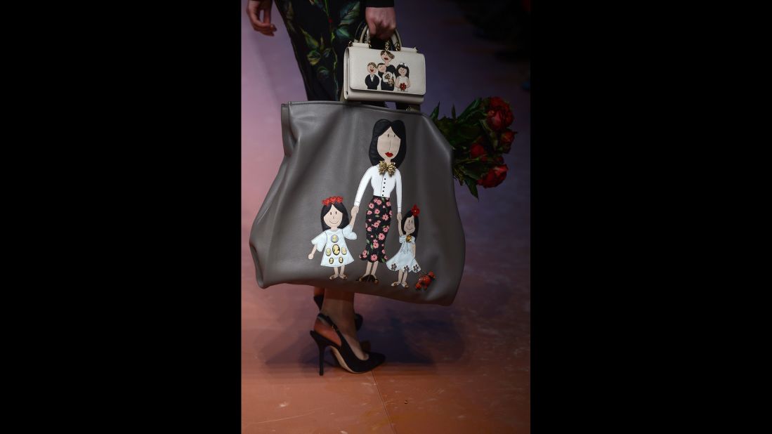 A model carries bags featuring embellished family drawings for Dolce & Gabbana's fall/winter collection.