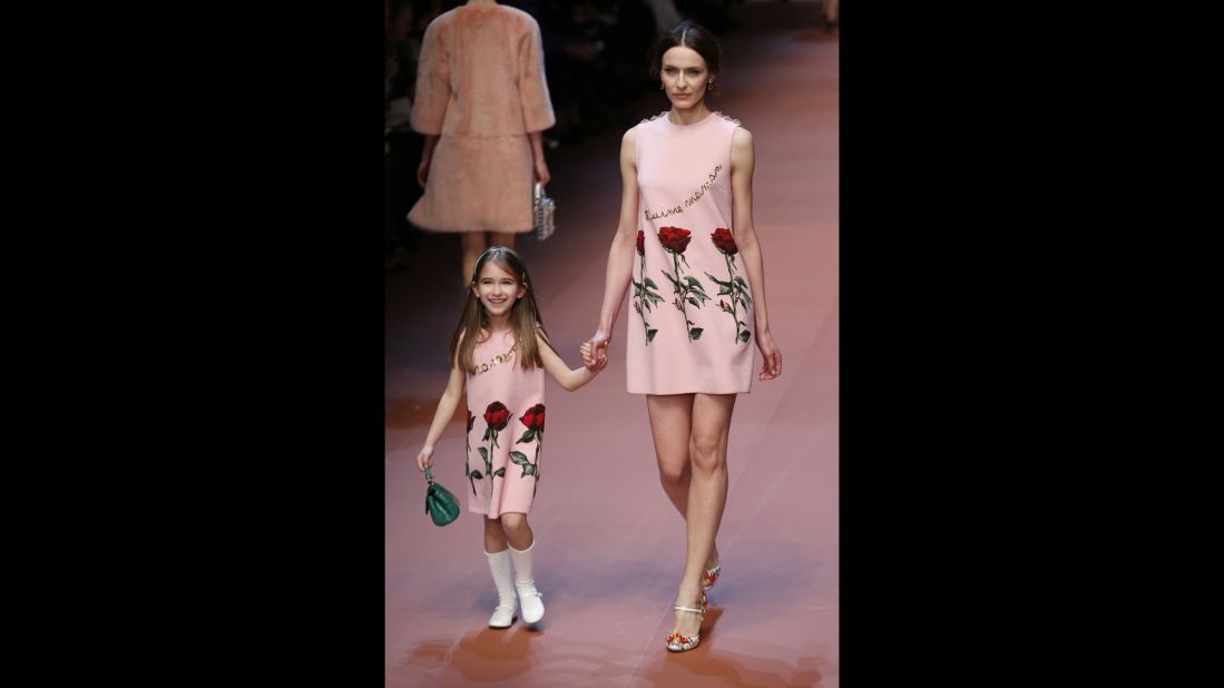 A mother and daughter wear matching dresses down the runway. The writing on the dresses reads, "I love you, mom."