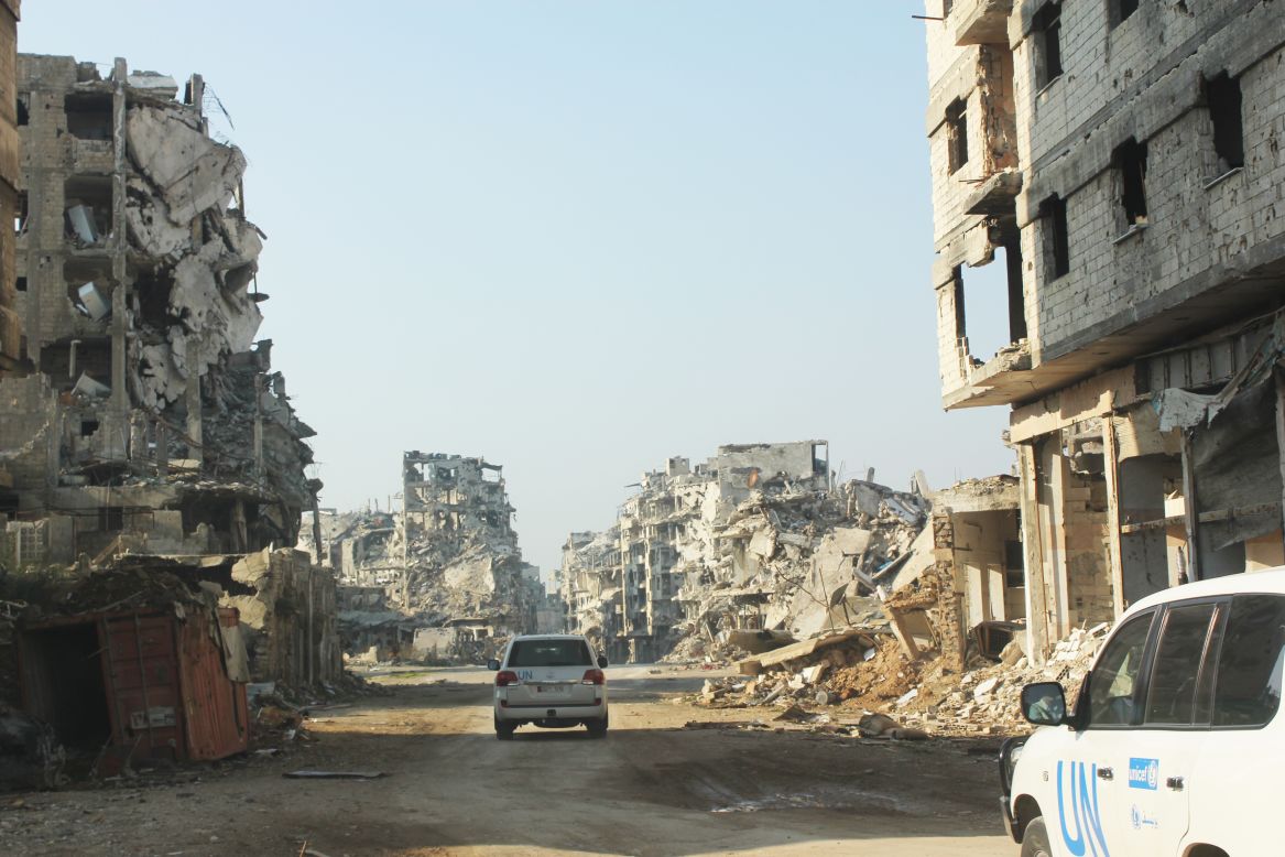 UNICEF vehicles travel a dusty road lined with remnants of buildings in the Old City of Homs, Syria. UNICEF has 380 staff working on the Syrian crisis, 180 inside Syria. 