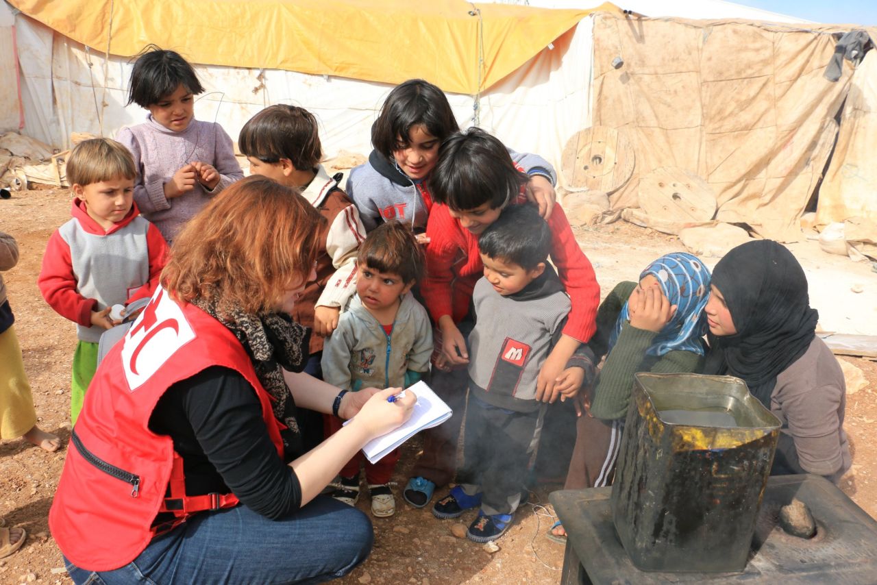 A Red Crescent volunteer speaks with Syrian refugees in Jordan. The International Federation of the Red Cross and Red Crescent Societies help 3.7 million Syrians each month. About 3,000 IFRC volunteers are working with the Syrian crisis and  47 IFRC volunteers have died in the line of duty.