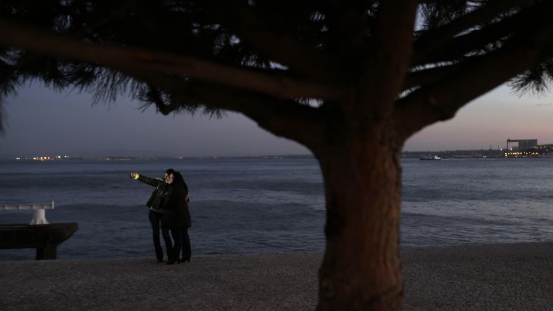After sundown, two women pose for a selfie by the Tagus riverbank in Lisbon, Portugal, on Friday, February 27.