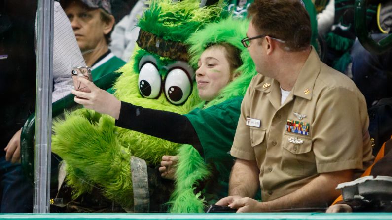 Dallas Stars mascot Victor E. Green poses with a fan during an NHL hockey game on Sunday, March 1.