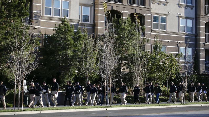 Federal agents walk by an upscale apartment complex, where authorities say a birth tourism business charged pregnant women $50,000 for lodging, food and transportation.