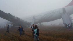 Passengers walk away from a Turkish Airlines plane after it skidded off the runway while landing at Kathmandu airport in the Nepalese capital Kathmandu on March 4, 2015. Aviation officials said no one on board was injured, although one witness described how terrified passengers leapt from their seats as the cabin filled with smoke after the plane skidded to a halt. AFP PHOTO / Dikesh Malhotra        (Photo credit should read Dikesh Malhotra/AFP/Getty Images)