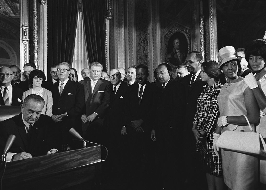 President Lyndon B. Johnson signs the Voting Rights Act in August 1965 as the Rev. Martin Luther King Jr. looks on. The law boosted access to the polls and reshaped the South.