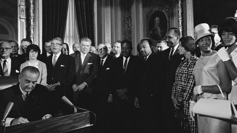 President Lyndon B. Johnson signs the Voting Rights Act in August 1965 as the Rev. Martin Luther King Jr. looks on. 