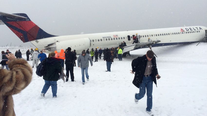 In this photo provided by passenger Amber Reid, passengers are evacuated after a Delta plane skidded off the runway while landing at LaGuardia Airport during a snowstorm, Thursday, March 5, 2015, in New York. Authorities said the plane, from Atlanta, carrying 125 passengers and five crew members, veered off the runway at around 11:10 a.m. before crashing through a chain-link fence and coming to rest with its nose perilously close to the edge of an icy bay. (AP Photo/Amber Reid)