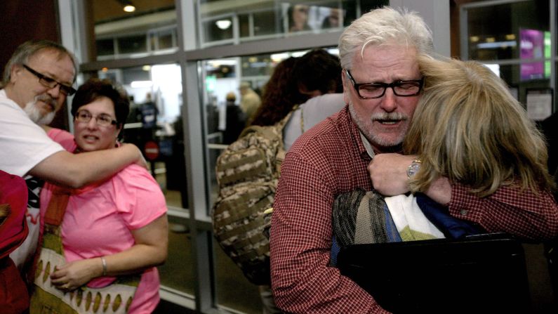 Aid workers Arlynn Hefta, right, and Kermit Paulson, left, embrace their wives Tuesday, March 3, at an airport in Fargo, North Dakota. Hefta and Paulson were among four American missionaries who were released by Venezuelan authorities after several days of questioning.