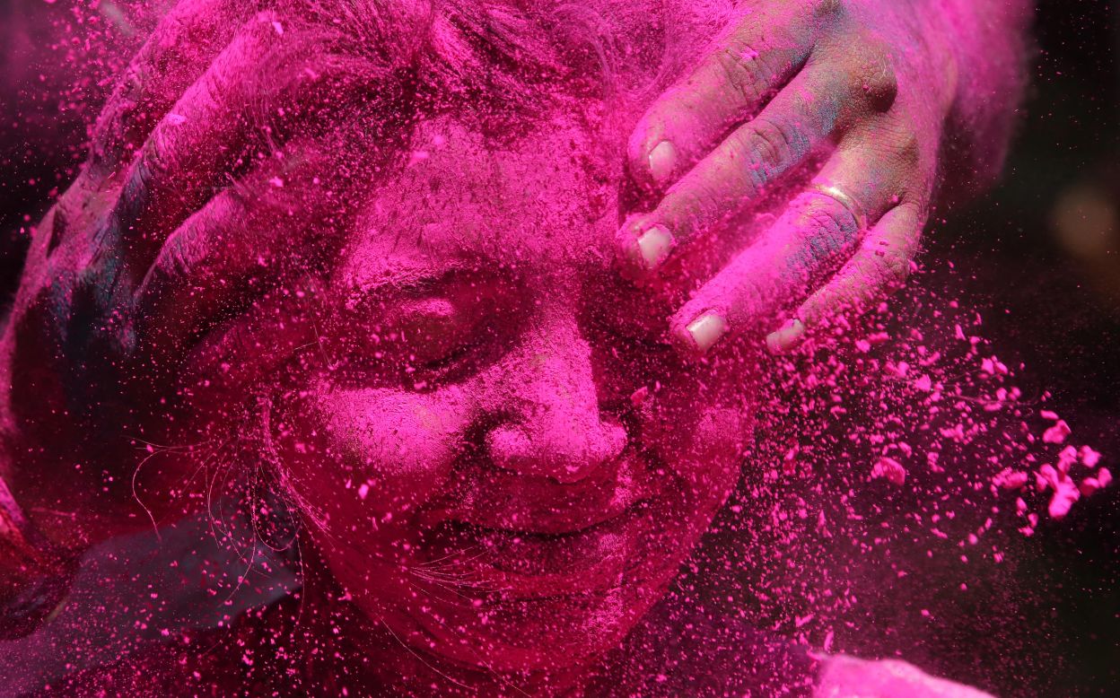 A woman shuts her eyes as colored powder is smeared on her face during Holi celebrations in Mumbai, India, on Friday, March 6. 