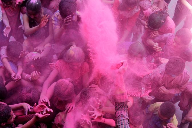 A teacher throws colored powder on children at a school in Ahmadabad, India, on Thursday, March 5.