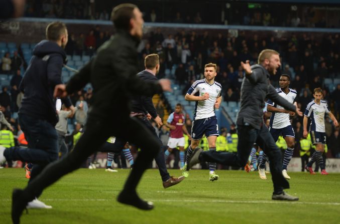 West Brom and Scotland midfielder James Morrison looks on as excitable Aston Villa fans celebrate their sides second goal. West Brom manager Tony Pulis later described the pitch-invading fans as "mindless idiots" in a post-match interview with the BBC.