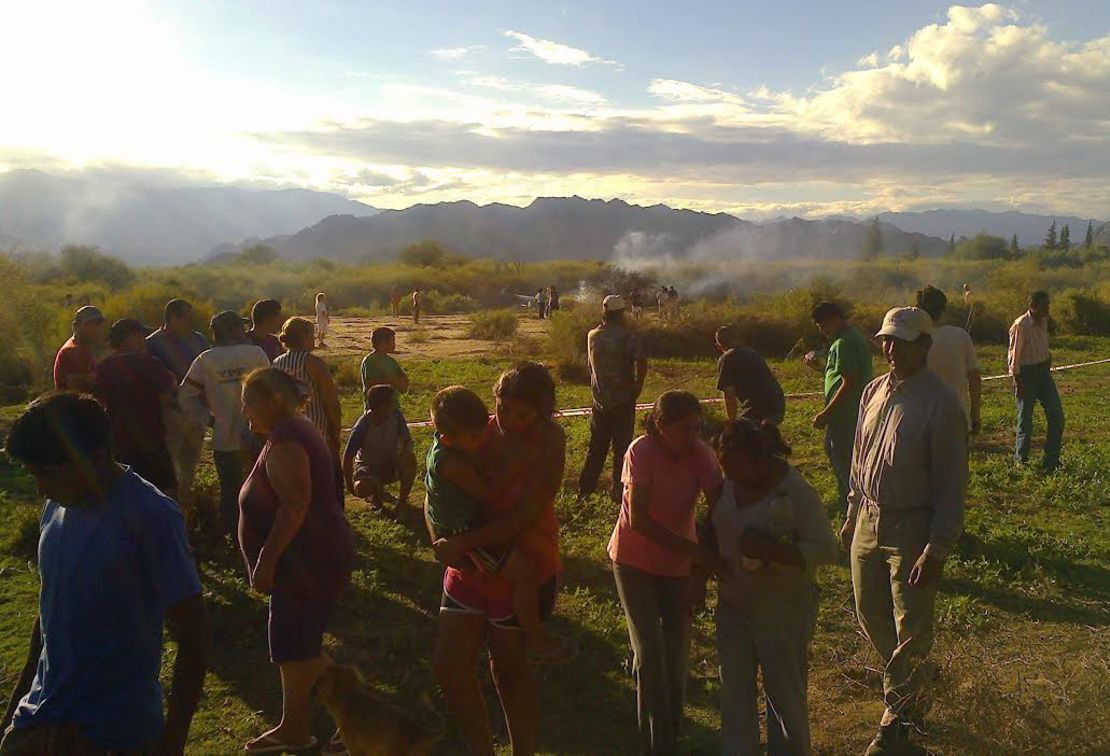 People gather close to the smoking wreckage near Villa Castelli, Argentina. 
