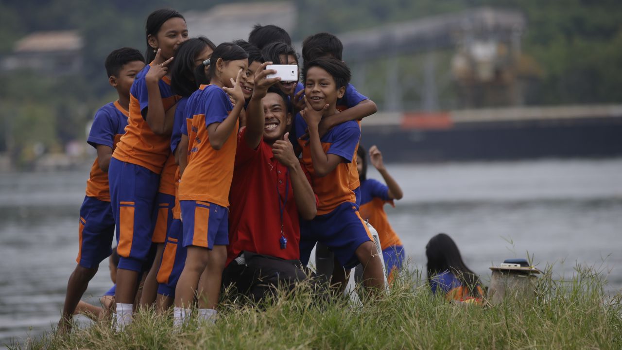 A teacher and students take a photo Thursday, March 5, at the Wijaya Pura port in Cilacap, Indonesia.