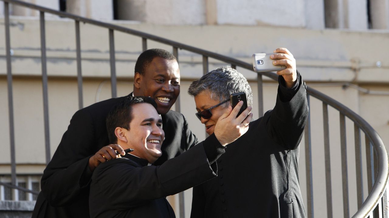 Priests in Rome snap selfies as they wait for the arrival of Pope Francis on Saturday, March 7.