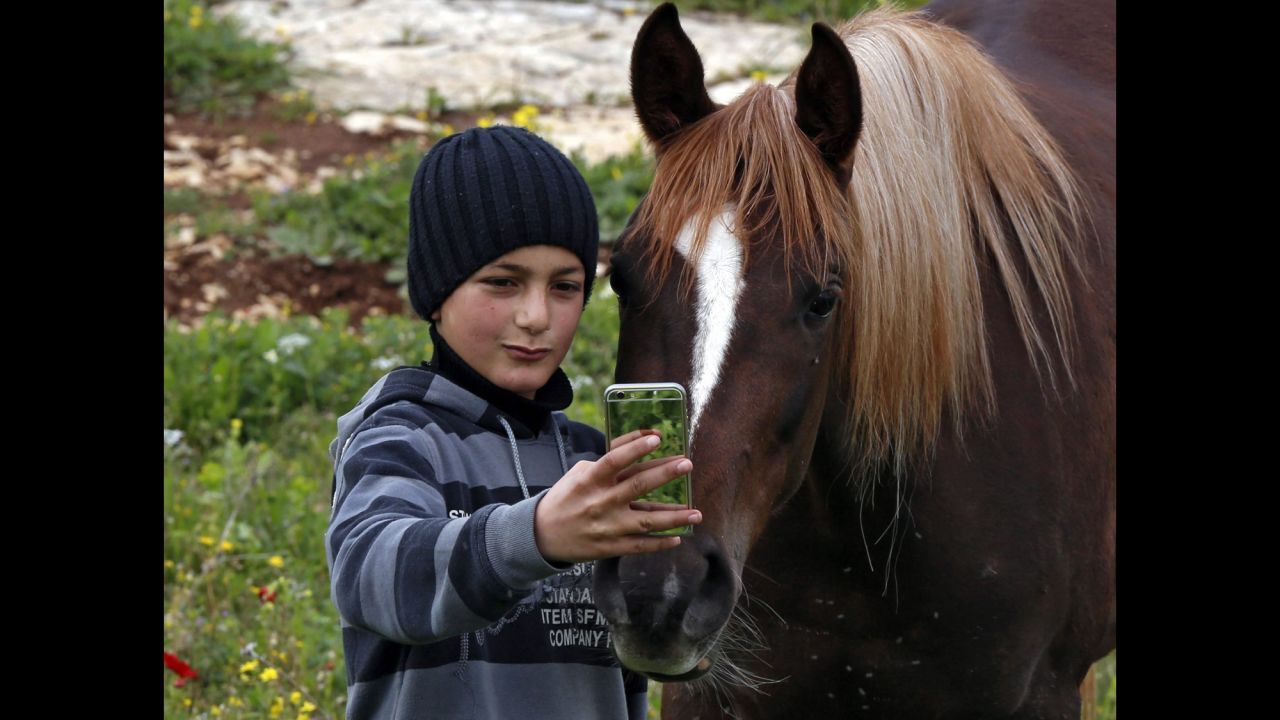 A boy takes a photo with a horse at his family farm near the West Bank city of Nablus on Wednesday, March 4.