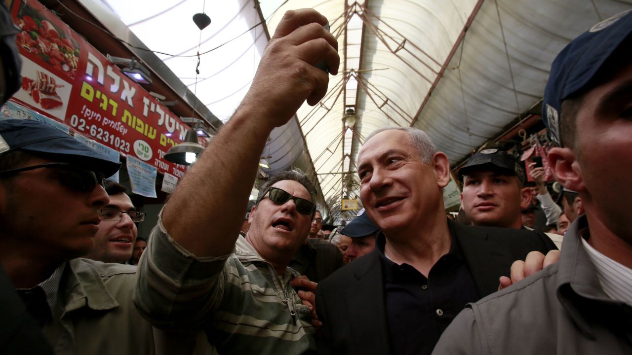 A man takes a selfie with Israeli Prime Minister Benjamin Netanyahu as Netanyahu campaigns at a Jerusalem market on Monday, March 9.