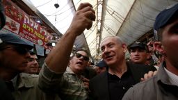 Surrounded by body guards, Israeli Prime Minister and head of the Likud party Benjamin Netanyahu (C-R) poses for a selfie with a supporter as he visits the Jerusalem outdoors Mahane Yehuda market on March 9, 2015 during his campaign for the upcoming general election on March 17.