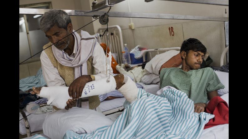 Dharmender's father, Mahaveer, helps him to move on the bed a few days after his operation.