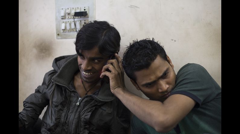 A friend holds a cell phone to Kumar's ear as he talks to his mother in November.